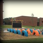 Tires and outdoor chalkboard installed on a playground at an Elementary School in Raleigh NC to help children continue developing gross motor skills while playing in a colorful environment.