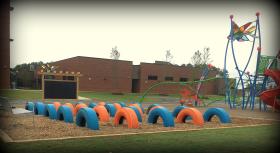 Tires and outdoor chalkboard installed on a playground at an Elementary School in Raleigh NC to help children continue developing gross motor skills while playing in a colorful environment.